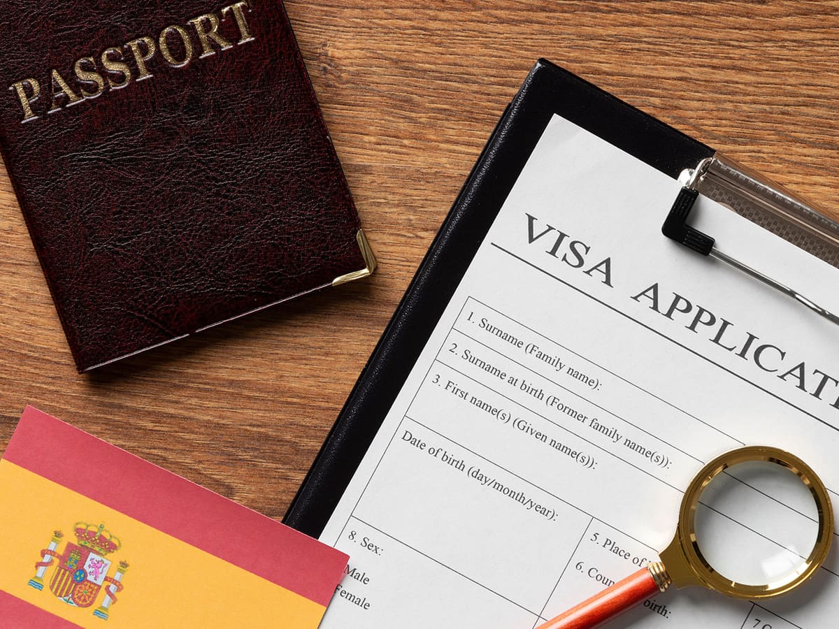 Passaporte e formulário de pedido de visto ao lado da bandeira da Espanha