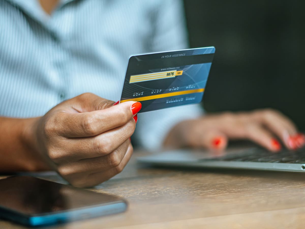 Mãos segurando um cartão de identificação diante do computador