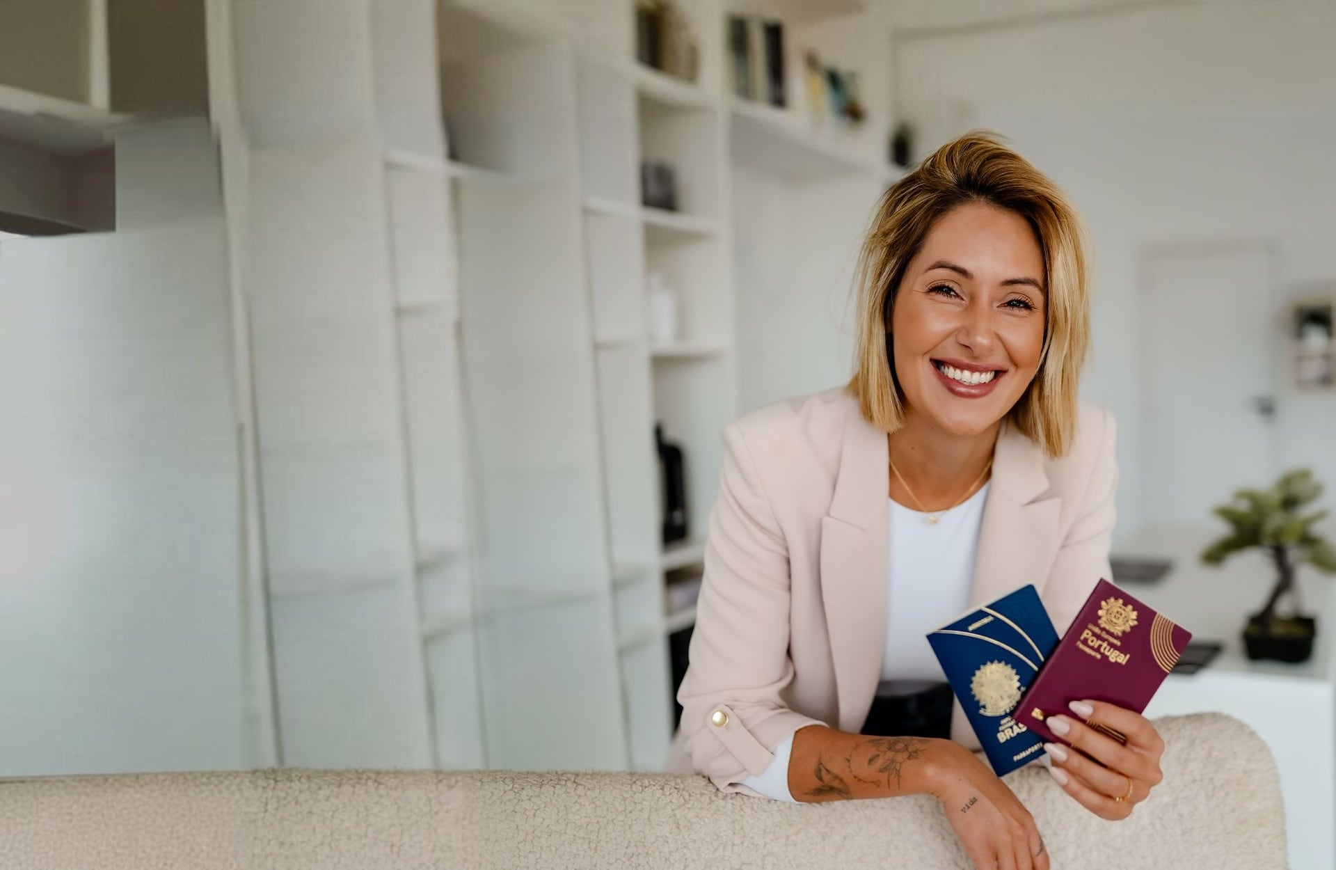 Carolina Vogels, advogada luso-brasileira, sorrindo com os passaportes brasileiro e português no escritório