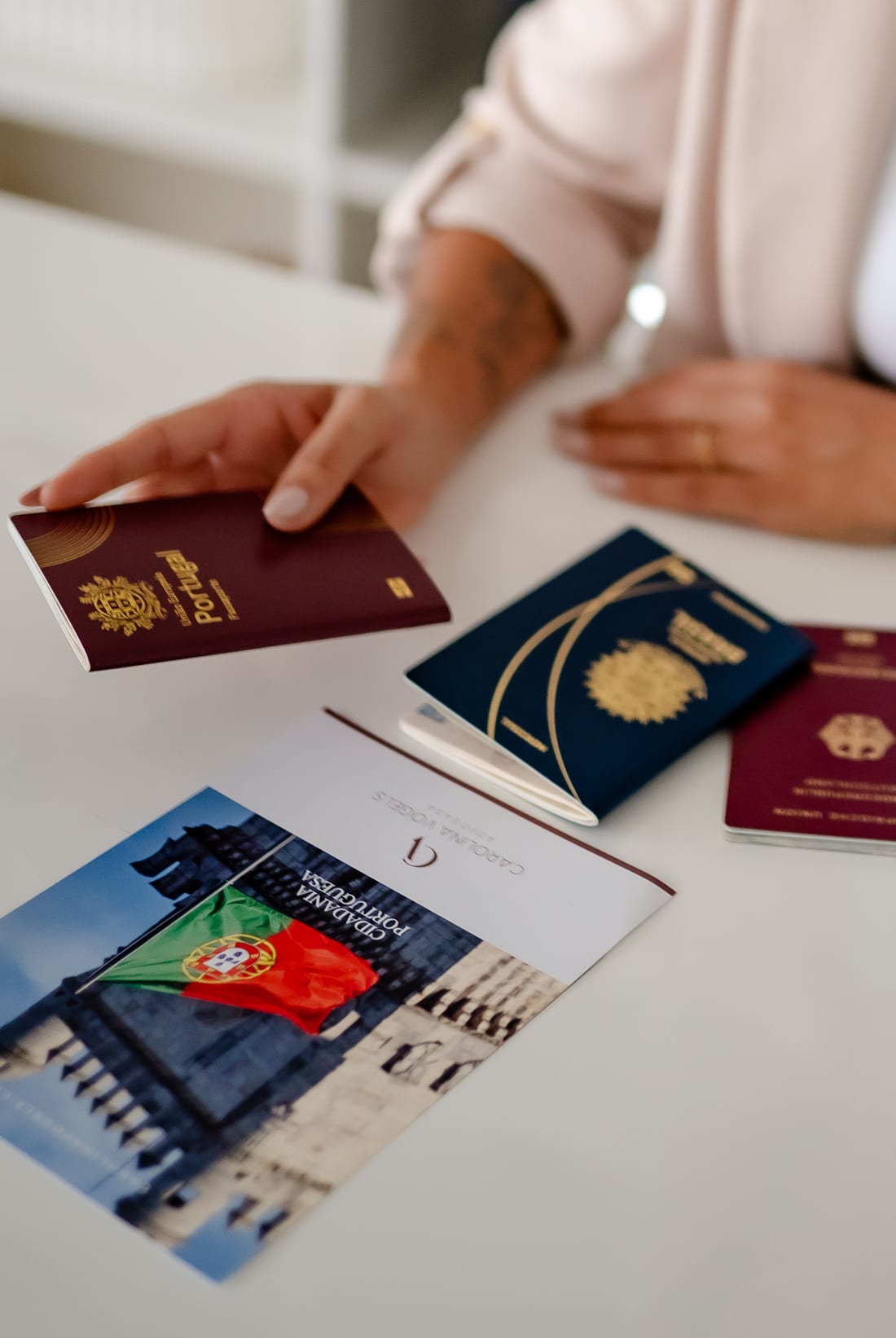 Passaportes português e brasileiro sobre a mesa, ao lado do material de cidadania portuguesa da Carolina